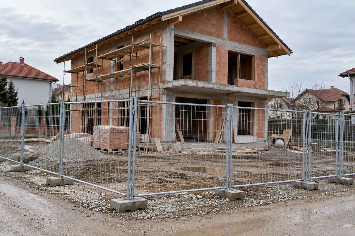 Gradilište porodične kuće ograđeno mobilnim metalnim ogradama postavljenim na betonske stope.